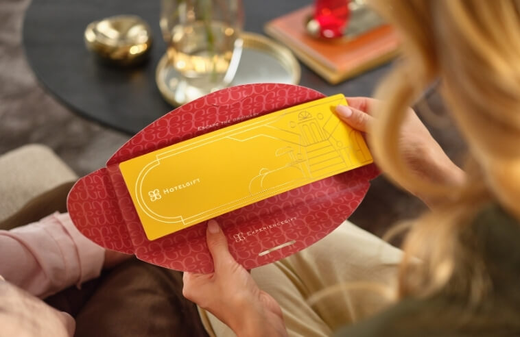 A Hotelgift voucher being lifted out of a red gift envelope